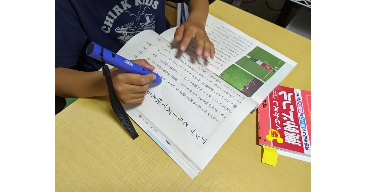 ペンでタッチすると読み上げる音声付教科書を使うむすこ